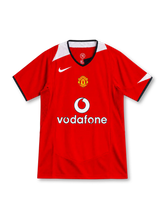 Manchester United 2004–06 red home jersey with white Nike Swoosh, black-trimmed V-neck, white shoulder accents, club crest and Vodafone sponsor.
