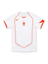 Netherlands 2004 white away jersey with orange Nike Swoosh, central KNVB lion emblem, curved orange piping, V-neck insert and orange sleeve accents.