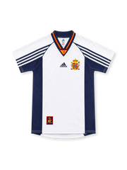 Spain 1998 white away jersey with navy side panels, adidas three-stripe sleeves, red-and-yellow V-neck trim, Spanish federation crest and lower-hem emblem.