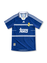 Real Madrid 1998/99 blue away jersey with white horizontal chest stripes, adidas three-stripe shoulders, white polo collar, club crest and Teka sponsor.