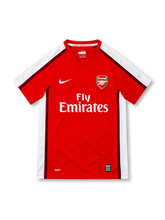 Arsenal 2008/10 red home jersey by Nike with white shoulder panels, burgundy piping, V-neck collar, Arsenal crest, white Fly Emirates sponsor and NikeFIT branding.