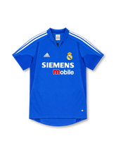 Real Madrid 2004/05 royal-blue third jersey with white adidas shoulder stripes, blue fold-down collar, club crest, Siemens mobile chest sponsor and ClimaCool branding.