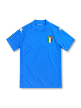 Italy 2002 azure-blue home jersey by Kappa with a matching rounded collar, white Omini shoulder logos, Italian tricolor shield crest and yellow sleeve star detailing.