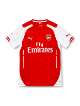 Arsenal 2014/15 red home jersey with white sleeves and side panels, red crew-neck collar, white Puma logos, Arsenal club crest, Fly Emirates sponsor and DryCell branding.