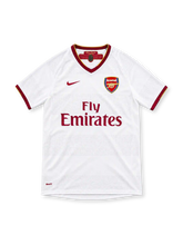 Arsenal 2007/08 white Nike away jersey featuring a claret V-neck collar with gold trim, matching sleeve cuffs, claret Nike Swoosh, Arsenal crest, Fly Emirates sponsor and commemorative inner-neck detail.