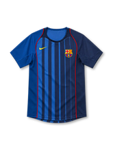 Barcelona 2004/05 Nike away jersey with royal-blue and navy vertical stripes, red piping along the front, contrasting blue sleeves, yellow Nike Swoosh, Barcelona crest, and rounded neckline.