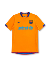 Barcelona 2006/07 orange Nike away jersey with blue-and-red V-neck trim, dark-blue Nike Swoosh, Barcelona club crest, light-blue UNICEF chest logo, and matching sleeve and hem detailing.