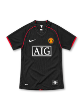 Manchester United 2007/08 black Nike away jersey with red curved shoulder piping, black V-neck collar, white Nike Swoosh, Manchester United crest, rectangular white AIG sponsor and NikeFIT branding.