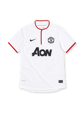 Manchester United 2012/13 white Nike away jersey featuring a red-trimmed Henley collar, red sleeve cuffs, black Nike Swoosh, monochrome club crest, black Aon sponsor and Dri-FIT branding.