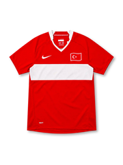 Türkiye 2008 red Nike home jersey featuring a wide white horizontal chest stripe, white-trimmed V-neck collar, white Nike Swoosh, Turkish crescent-and-star flag emblem, and NikeFIT branding.