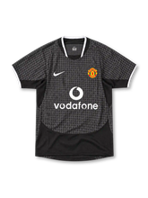 Manchester United 2003/05 Nike away jersey in black and charcoal grey with an all-over geometric pattern, white-trimmed collar and sleeve cuffs, white Nike Swoosh, Manchester United crest and Vodafone sponsor.
