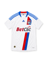 Olympique Lyonnais 2010/11 white adidas home jersey with blue shoulder stripes, red and blue diagonal accents, OL crest, Betclic sponsor, commemorative 1950–2010 neckline detail, and ClimaCool branding.