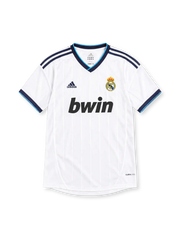 Real Madrid 2012/13 white adidas home jersey with subtle vertical pinstripes, navy shoulder stripes, navy and turquoise V-neck collar, crowned club crest, black bwin sponsor, and ClimaCool branding.
