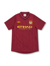 Manchester City 2012/13 Umbro away jersey in deep maroon with tonal vertical pinstripes, layered V-neck collar, gold Umbro logo, three-star club crest, and gold Etihad Airways sponsor.