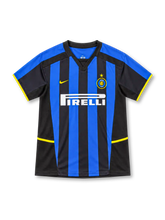 Inter Milan 2002/03 Nike home jersey featuring blue-and-black vertical stripes, black V-neck collar, yellow Nike logo, Inter crest with gold star, white Pirelli sponsor, and yellow sleeve and side accents.
