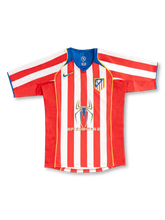 Back view of Atletico Madrid 2004/05 home jersey with red and white stripes, blue upper-back panel and yellow piping.