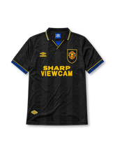 Manchester United 1993-94 away jersey, front view, black body with tonal diamond jacquard pattern, gold and blue striped collar, Umbro diamond logo, club crest, SHARP Viewcam sponsor logo, gold and blue diamond cuffs