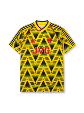 Arsenal 1991-93 away jersey, front view, yellow body with black gradient zigzag pattern, yellow V-neck collar with black and red trim, red piping, adidas trefoil logo, club cannon crest, JVC sponsor logo, striped sleeve trim