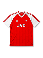 Arsenal 1988-90 home jersey, front view, red body with white raglan sleeves, adidas three-stripe sleeve trim, white V-neck collar with black inner trim, adidas trefoil logo, club cannon crest, JVC sponsor logo, striped cuffs