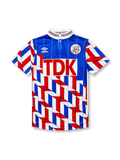 Ajax 1989-90 away jersey, front view, blue upper body with pinstripes, red white and blue geometric chevron pattern on lower body and sleeves, striped funnel collar, Umbro diamond logo, club crest, TDK sponsor logo
