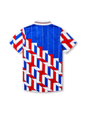Ajax 1989-90 away jersey, front view, blue upper body with pinstripes, red white and blue geometric chevron pattern on lower body and sleeves, striped funnel collar, Umbro diamond logo, club crest, TDK sponsor logo