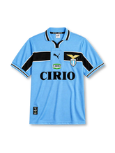 Lazio 1998-99 home jersey, front view, sky blue body with black chest and sleeve band, striped V-neck collar with S.S. Lazio text, Puma logo, club eagle crest, CIRIO sponsor logo, striped cuffs