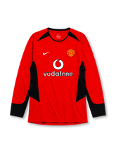 Manchester United 2002-04 home long sleeve jersey, front view, red body with black angular shoulder and side panels, black crew neck collar, black forearm panels, Nike swoosh logo, club crest, Vodafone sponsor logo