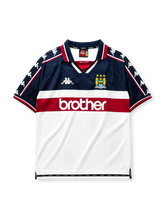 Manchester City 1997-98 away jersey, front view, navy upper body with white and maroon lower blocks, point collar with M.C.F.C. text, Kappa Omini sleeve pattern, club crest, Brother sponsor logo
