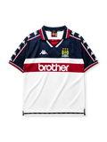 Manchester City 1997-98 away jersey, front view, navy upper body with white and maroon lower blocks, point collar with M.C.F.C. text, Kappa Omini sleeve pattern, club crest, Brother sponsor logo