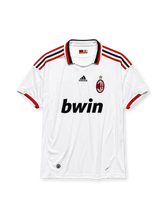 AC Milan 2009-10 away jersey, front view, white body, red and black adidas three-stripe shoulder detailing, point collar with Forza Milan flag tab, adidas logo, club crest with championship star, bwin sponsor logo, red-trimmed cuffs