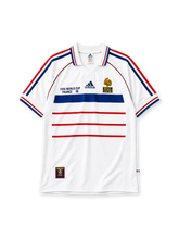 France 1998 World Cup final away jersey, front view, white body with blue and red horizontal stripes, striped raglan sleeves, point collar, FIFA World Cup France 98 text, adidas logo, rooster crest with Bresil France 12-07-98 text, striped cuffs