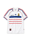 France 1998 World Cup final away jersey, front view, white body with blue and red horizontal stripes, striped raglan sleeves, point collar, FIFA World Cup France 98 text, adidas logo, rooster crest with Bresil France 12-07-98 text, striped cuffs