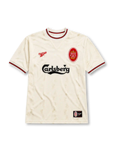 Liverpool 1996-97 away jersey, front view, ecru body with subtle jacquard pattern, red and black striped collar and cuffs, red Reebok logo, oval red and white Liverpool crest, black Carlsberg sponsor logo, woven tag near bottom hem