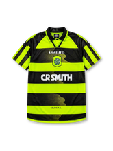 Celtic 1996-97 away jersey, front view, neon-yellow and black hooped design, black polo-style collar, diagonal striped raglan sleeves, white Umbro logo, Celtic shield crest with shamrock, white CR Smith sponsor logo, Celtic F.C. text near hem