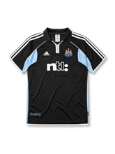 Newcastle United 2000-01 away jersey, front view, black body with sky blue side panels, black polo-style collar, white adidas logo and stripes, Newcastle United shield crest, white ntl sponsor logo, authentic product tag near hem