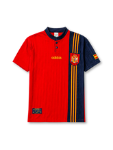 Spain 1996 home jersey, front view, red body with asymmetric navy side panel, navy button-placket collar, yellow adidas logo and stripes, Spanish royal crest, small Spain flag patch on sleeve, Federacion Espanola de Futbol tag near hem