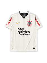Corinthians 2011 home jersey, front view, cream body with tonal vertical stripes, black crew-neck collar, gold Nike swoosh, centenary crest with four gold stars and 1910-2010 text, black Neo Quimica sponsor logo, red Bozzano sponsor text on sleeves
