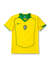 Brazil 2004 home jersey, front view, yellow body with green V-neck collar, curved seam piping, Nike swoosh logo, CBF crest with five stars, Brasil text