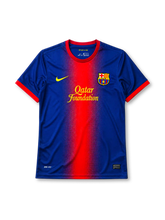 Barcelona 2012-13 home jersey, front view, blue body with red gradient center panel, red crew-neck collar, yellow Nike swoosh, Barcelona crest, yellow Qatar Foundation sponsor logo, red cuffs