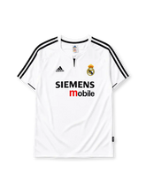 Real Madrid 2003-04 home jersey, front view, white body, black V-neck collar with button placket, black adidas logo and stripes, Real Madrid crest with crown, black and red Siemens mobile sponsor logo