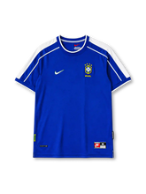 Brazil 1998 away jersey, front view, blue body with white raglan shoulder panels, white crew-neck collar with blue trim, red Nike swoosh, CBF crest with four stars, Brasil text beneath crest
