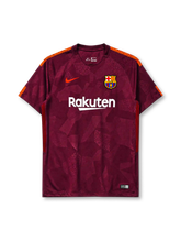 Barcelona 2017-18 third jersey, front view, deep maroon body with tonal geometric crackled pattern, orange shoulder accents, crew-neck collar, orange Nike swoosh, Barcelona crest, white Rakuten sponsor logo, black and red striped side panels
