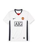 Manchester United 2008-09 away jersey, front view, white body with navy side panels, black V-neck collar with red inset and United text, black Nike swoosh, Manchester United crest, boxed AIG sponsor logo, NikeFIT wordmark near hem