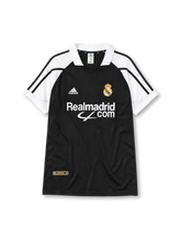 Real Madrid 2001-02 away jersey, front view, black body with white raglan sleeves, white polo-style collar, black adidas logo and stripes, Real Madrid crest with crown, white Realmadrid.com sponsor logo