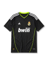 Real Madrid 2010-11 away jersey, front view, black body with subtle starburst pattern, neon green V-neck collar and side piping, white adidas logo and stripes, Real Madrid crest with crown, white bwin.com sponsor logo