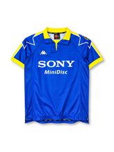 Juventus 1997-98 blue away jersey, front view, royal blue body, yellow polo collar with V-notch, yellow and blue star-point shoulder graphics with white outline, yellow cuffs, Juventus crest on left shoulder, Kappa logo on right chest, white SONY MiniDisc sponsor logo, mesh side panels, split side vents