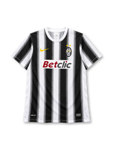 Juventus 2011-12 home jersey, front view, black and white vertical stripes with halftone edges, white crew neck collar, gold Nike swoosh on right chest, oval Juventus crest with two gold stars on left chest, BETCLIC sponsor logo on white panel, DRI-FIT print and Nike Authentic tag at hem