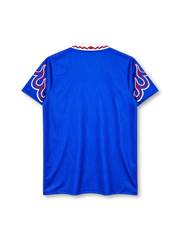 Japan 1996-97 home jersey, front view, royal blue body with tonal pattern, white polo collar with red and black stripe trim, red V insert, red white and blue flame graphics on both sleeves, white adidas wordmark on right chest, JFA crest with JAPAN text on left chest, official uniform label at hem