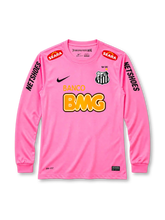 Santos 2013 pink long sleeve jersey, front view, pink body with long sleeves and ribbed cuffs, pink crew neck collar, red SEARA logos near shoulders, black NETSHOES lettering on sleeves, black Nike swoosh on right chest, Santos crest with crown and gold star on left chest, BANCO BMG sponsor logo