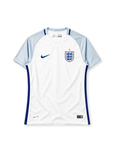 England 2016 home jersey, front view, white body, light blue textured raglan sleeves, V-neck collar, royal blue side panels, royal blue Nike swoosh on right chest, Three Lions crest with silver star on left chest, DRI-FIT print and Nike Authentic tag at hem